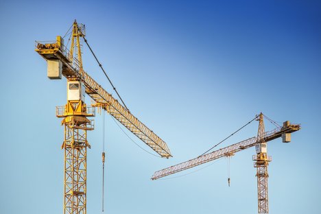 Zwei gelbe Baukräne vor einem blauen Himmel