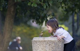 Mädchen trinkt aus einem Brunnen